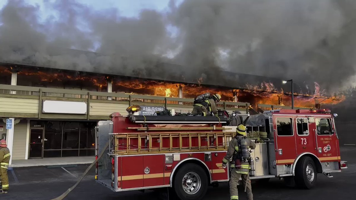 A second-alarm fire tore through the second floor of a strip mall near the corner of Lyons Avenue and Valley Street in Newhall this evening.   The fire was first reported to have started in a dumpster and quickly spread to the building before reaching the roof