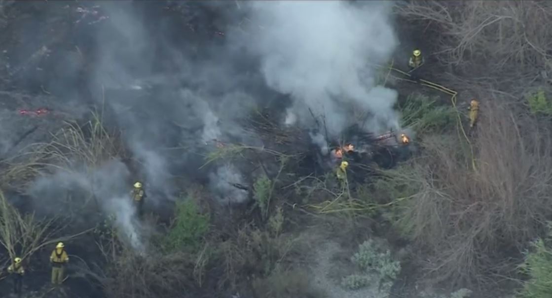 Firefighters are battling a small one-acre brush fire in Azusa, near a homeless encampment off Sierra Madre Avenue, north of Route 66