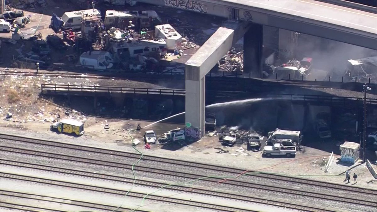 Firefighters continue to pour water on the fire burning under a freeway in the MacArthur Maze. Caltrans says motorists should avoid the area due to closures