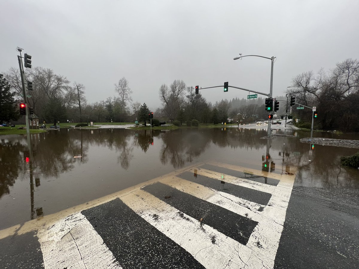 Santa Cruz County in the San Lorenzo Valley area. Notice the floodwaters waters taking over this intersection. People are standing around. It's dangerous