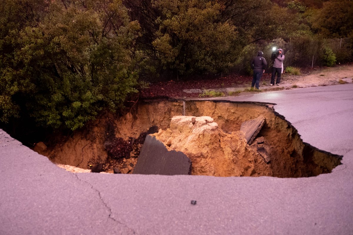 Cars remain in a large sinkhole along Iverson Road in Chatsworth Tuesday. A woman and a young girl are recovering after being trapped inside one of the vehicles   Monday night.  Los Angeles Fire Department rescuers pulled the victims to the surface