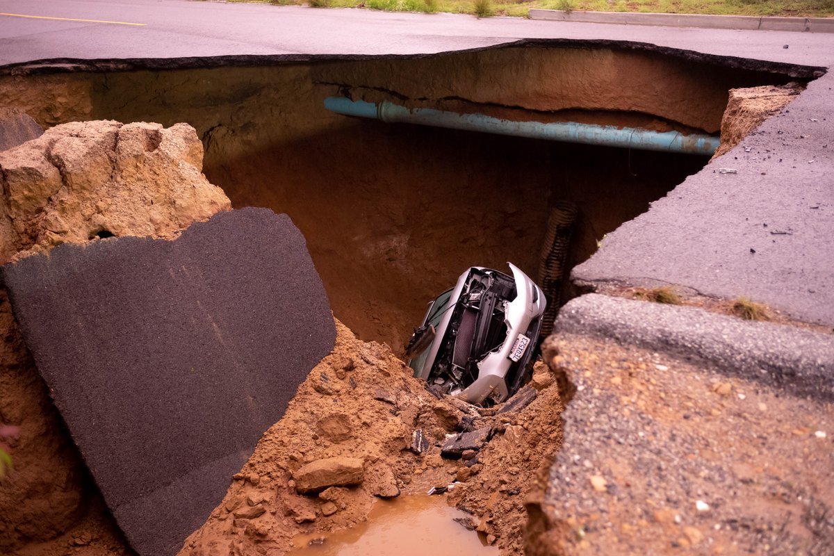 Cars remain in a large sinkhole along Iverson Road in Chatsworth Tuesday. A woman and a young girl are recovering after being trapped inside one of the vehicles   Monday night.  Los Angeles Fire Department rescuers pulled the victims to the surface