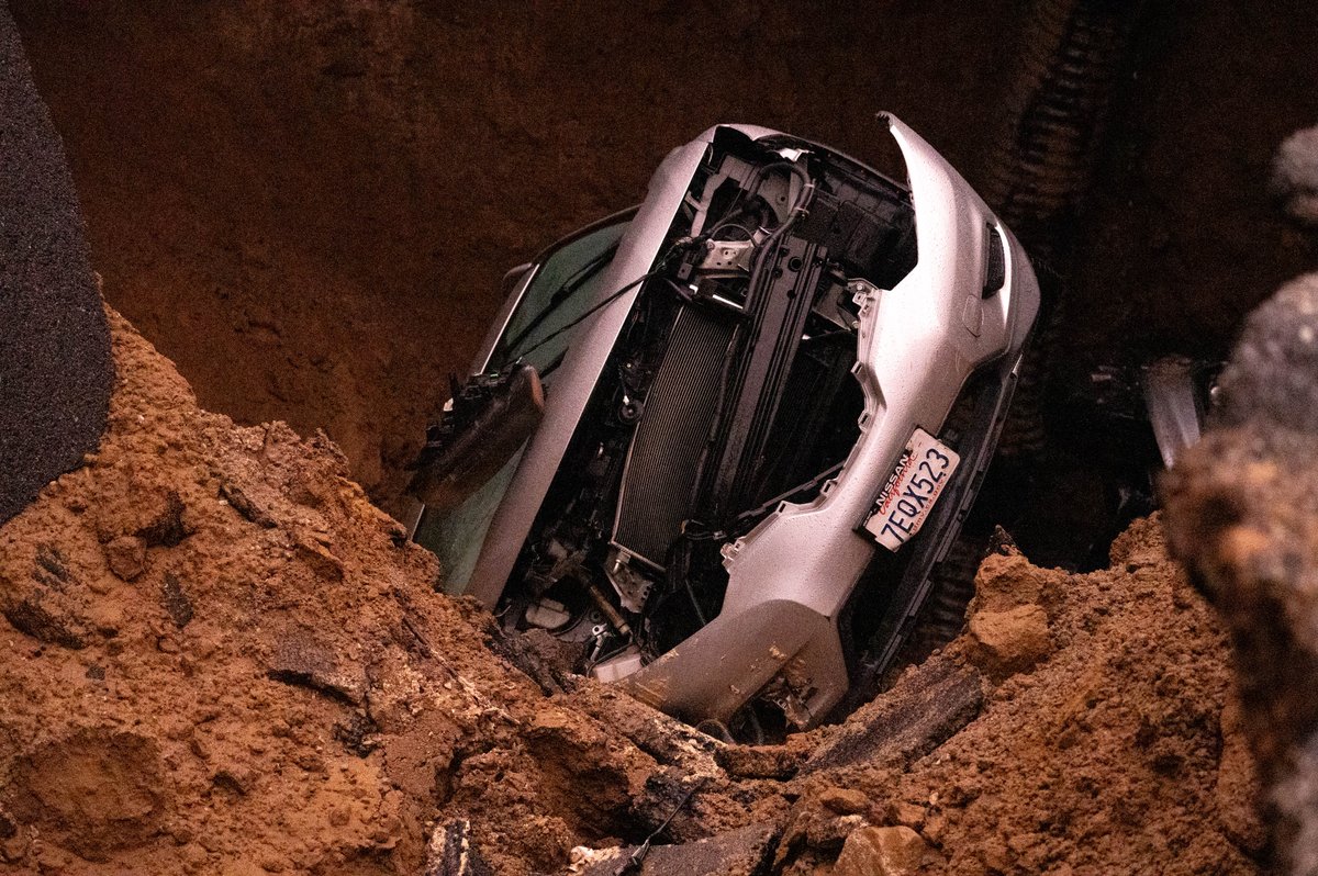 Cars remain in a large sinkhole along Iverson Road in Chatsworth Tuesday. A woman and a young girl are recovering after being trapped inside one of the vehicles   Monday night.  Los Angeles Fire Department rescuers pulled the victims to the surface